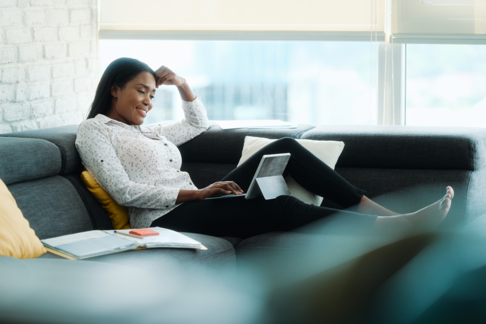 Portrait Of Businesswoman Doing Remote Work On Sofa woman working from home using her laptop on the couch.jpg